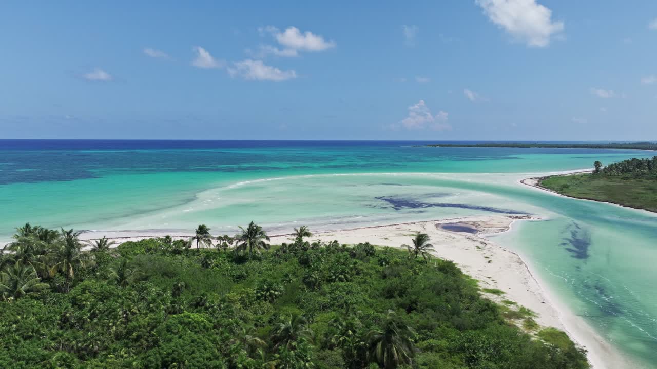 Un drone ascende diagonalmente sopra l'estuario e una spiaggia di sabbia bianca, con vista sulla splendida costa di Tulum.