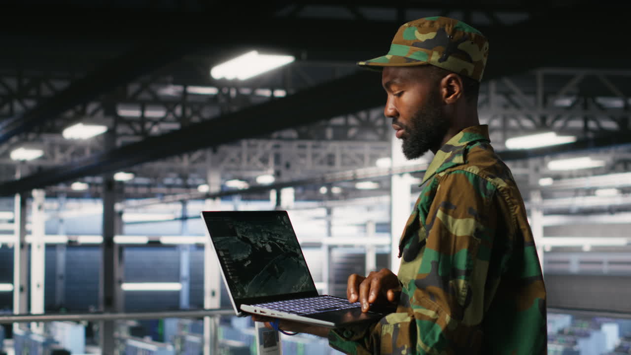 Military technician in data center monitoring warfare drone telemetry on laptop