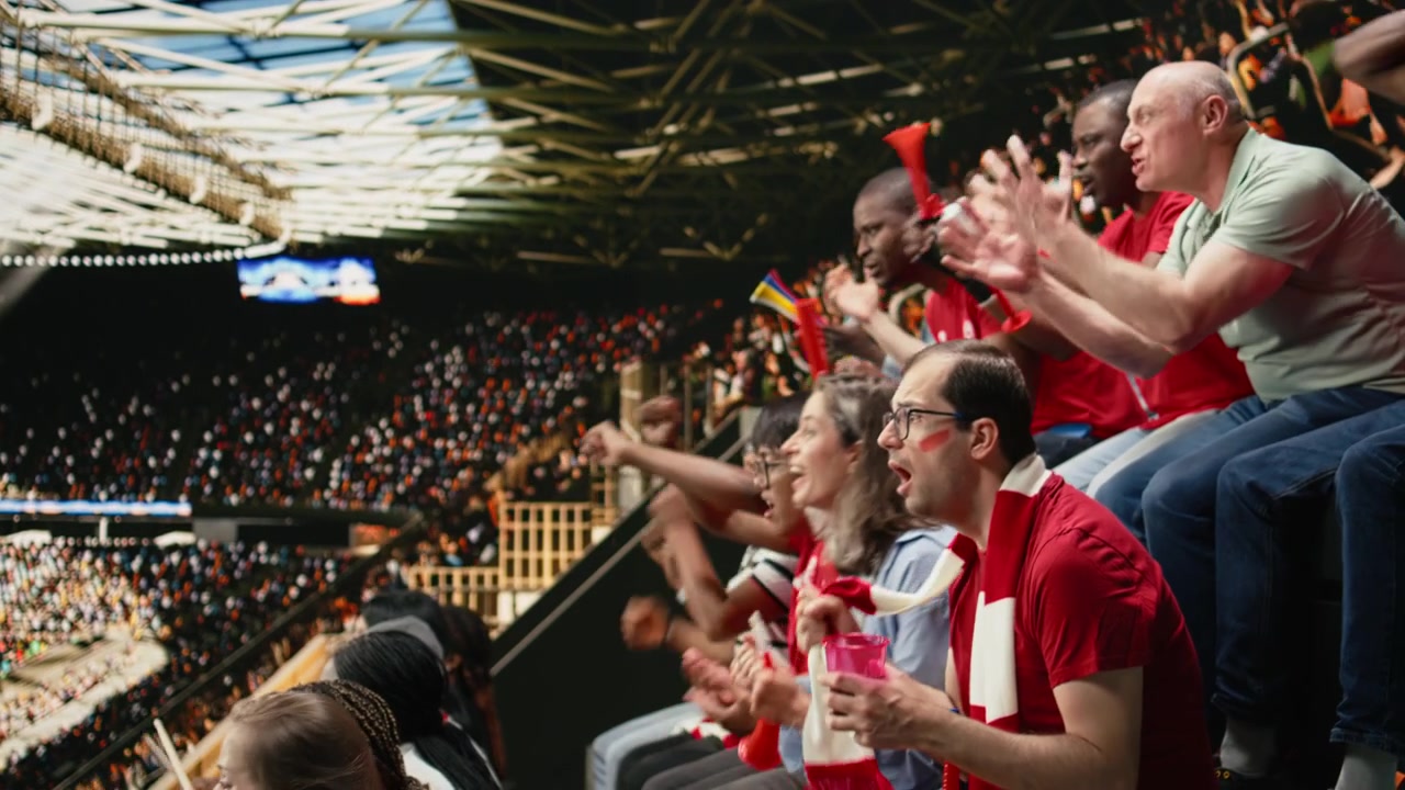 Voetbalfans van het rode team reageren op een nipte situatie op de stadiontribunes, met de handen op het hoofd
