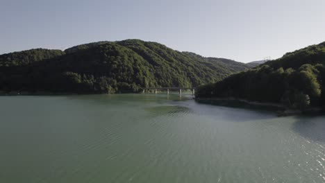 aerial view, approaching steel and concrete beam bridge over oasa lake, romania, part of the transalpine highway