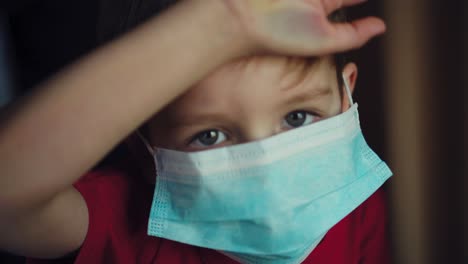 un niño con una máscara médica mira por la ventana 04