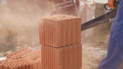 sunny close-up shot of this construction worker cutting sawing through bricks for a bricklayer wall, dust floats in the air with sun shining on the dustclouds