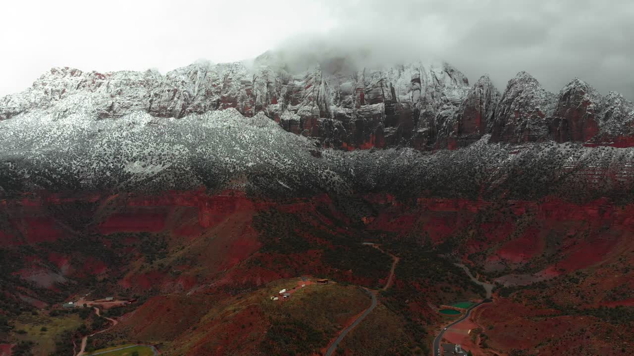 Aerial shot of a giant mountain in Utah Made of red rock and covered with snow on the peak