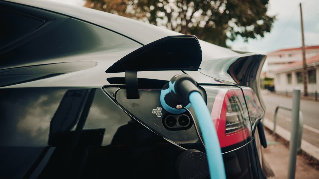 Şık siyah bir elektrikli arabaya bağlı bir şarj cihazının yakın çekim görüntüsü