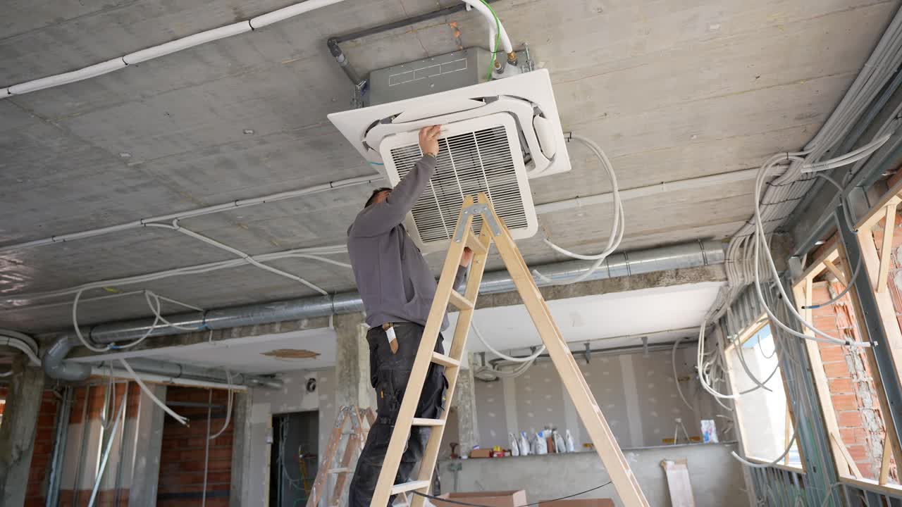 Man Installing Air Conditioning Unit on Ceiling at Construction Site