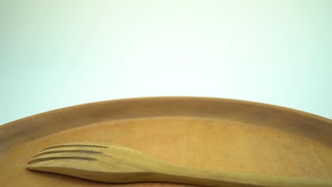 fotografía de cerca de un plato de madera vacío, un tenedor y una cuchara, con fondo blanco para el espacio de copia.