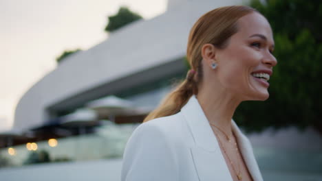 portrait smiling businesswoman walking evening street in elegant white suit.