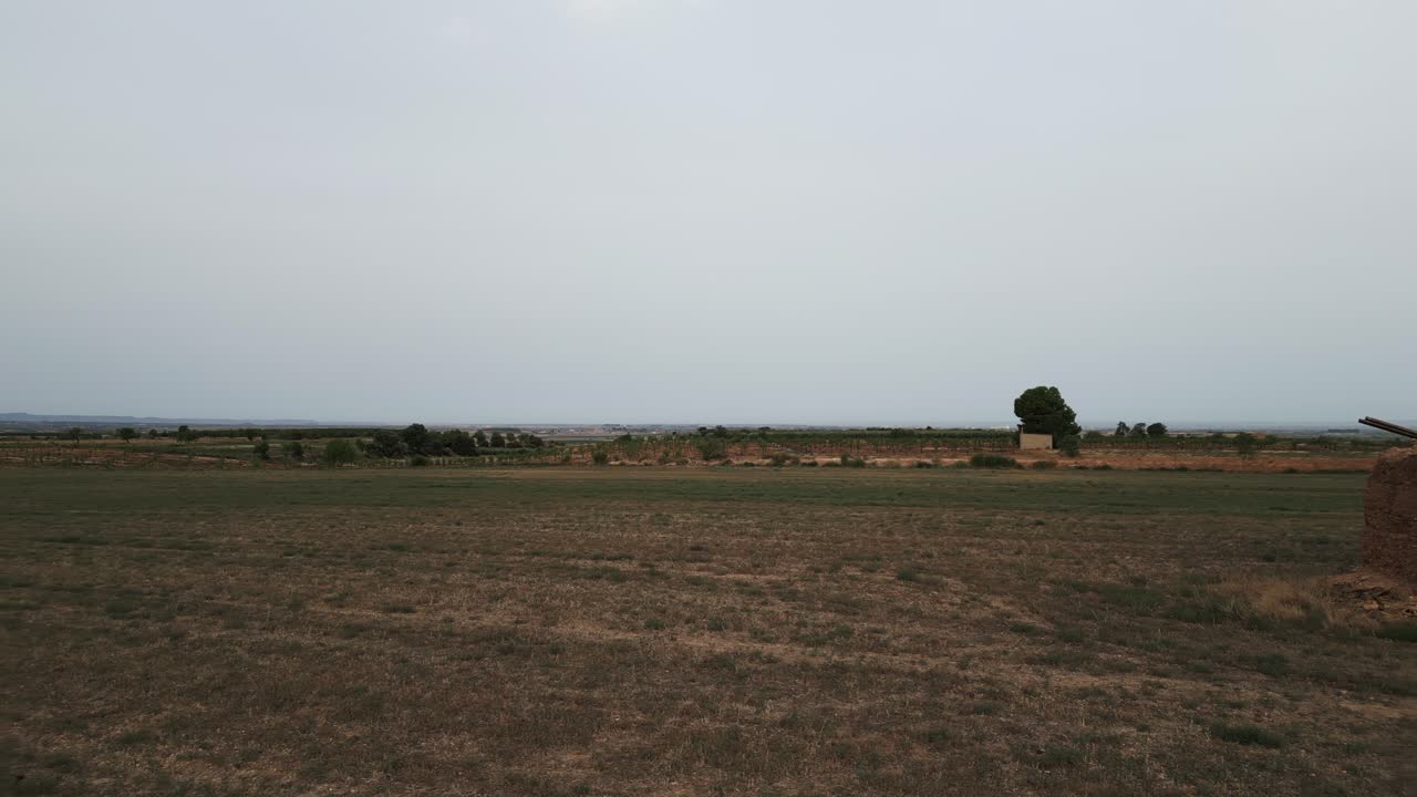 Aerial dolly right over field, passing by traditional tool shed, Tarrega, Spain
