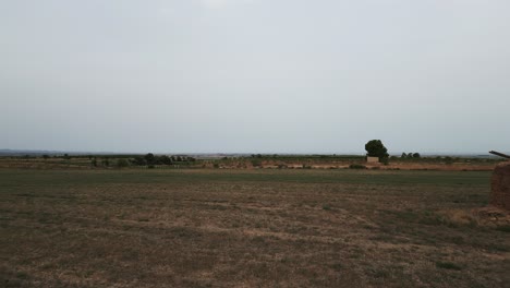 aerial dolly right over field, passing by traditional tool shed, tarrega, spain