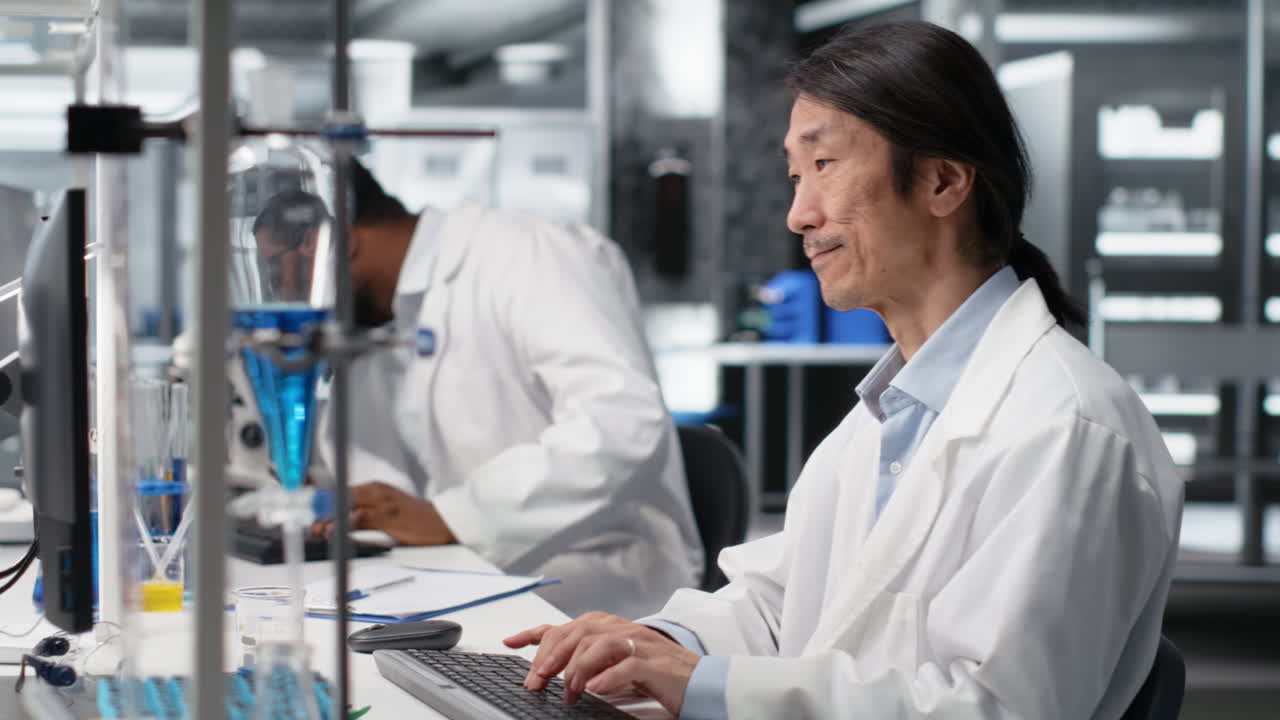 DNA患者のデータを処理するためにコンピューターを使用している、笑顔のアジア人研究者の縦型動画