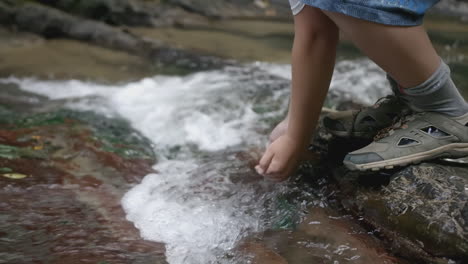 person drinking from a mountain stream