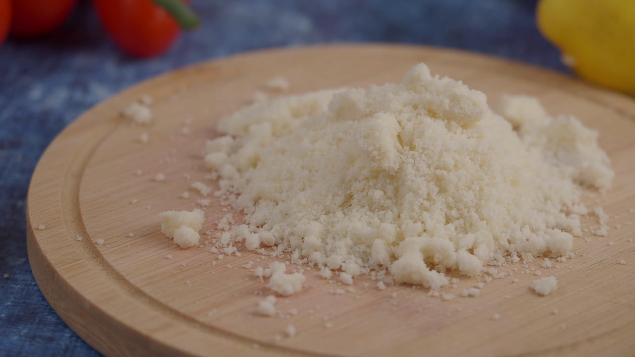 Close-up of Grated Parmesan Cheese on a Wooden Board with Fresh Ingredients