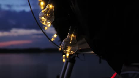 Glowing bulbs on camper tent sparkle gently in blue hour lakeside dusk