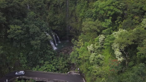 slowly rising above a deep hidden jungle waterfall below the winding narrow hana hwy, aerial
