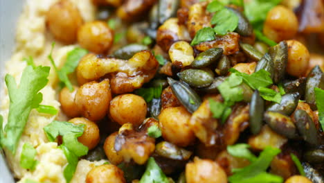 Houmous-with-chickpeas-parsley-and-seeds-in-a-bowl