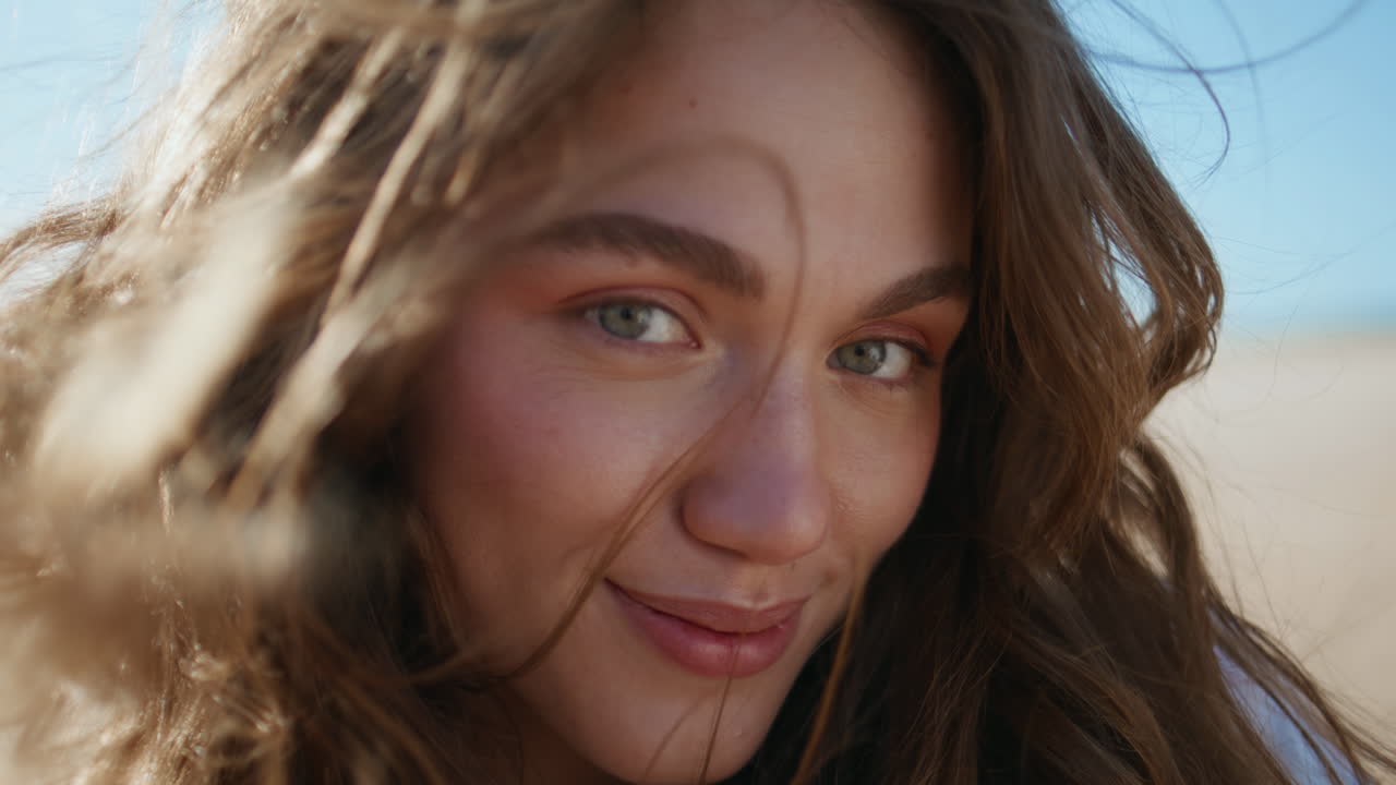 Wavy hair model smiling camera sea shore portrait. Cheerful woman ocean breeze