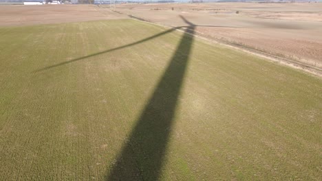 Sombra-De-Un-Enorme-Molino-De-Viento-Que-Gira-En-La-Pradera-De-Campo-Vista-Aérea-Del-Día-Soleado