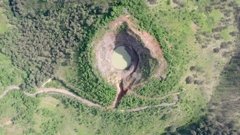 Aerial-video-captured-with-a-drone,-showcasing-a-mountain-with-a-hole-at-the-peak-and-a-water-filled-crater,-featuring-zenithal-view