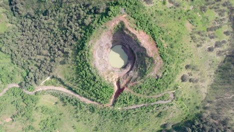 aerial video captured with a drone, showcasing a mountain with a hole at the peak and a water-filled crater, featuring zenithal view