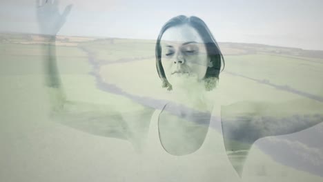 digital composition of caucasian woman meditating against aerial view of grassland