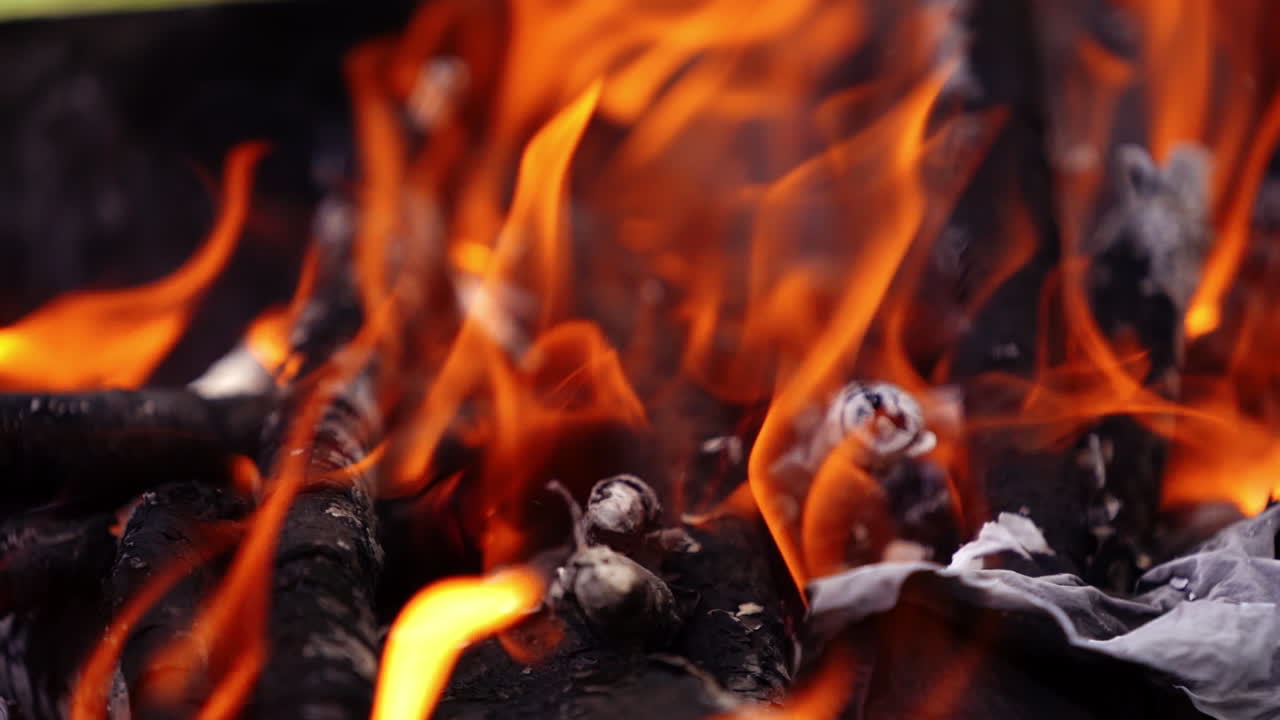 Fire burning in grill. Real fireplace full of wood and fire. Beautiful motion of vivid fire flame over the wooden logs. Charcoals in bright fire. Slow motion.