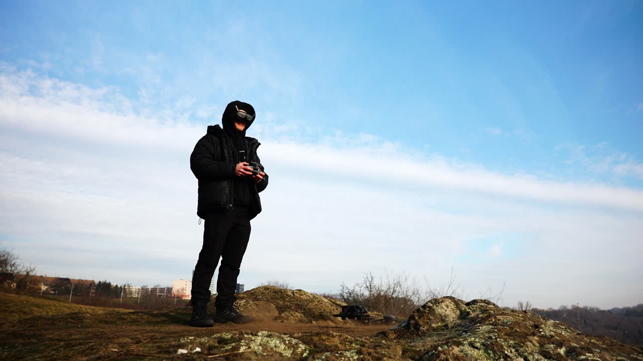 어두운 옷을 입은 남자가 fpv 드론 안경을 착용하고 이륙 기동을 수행합니다.