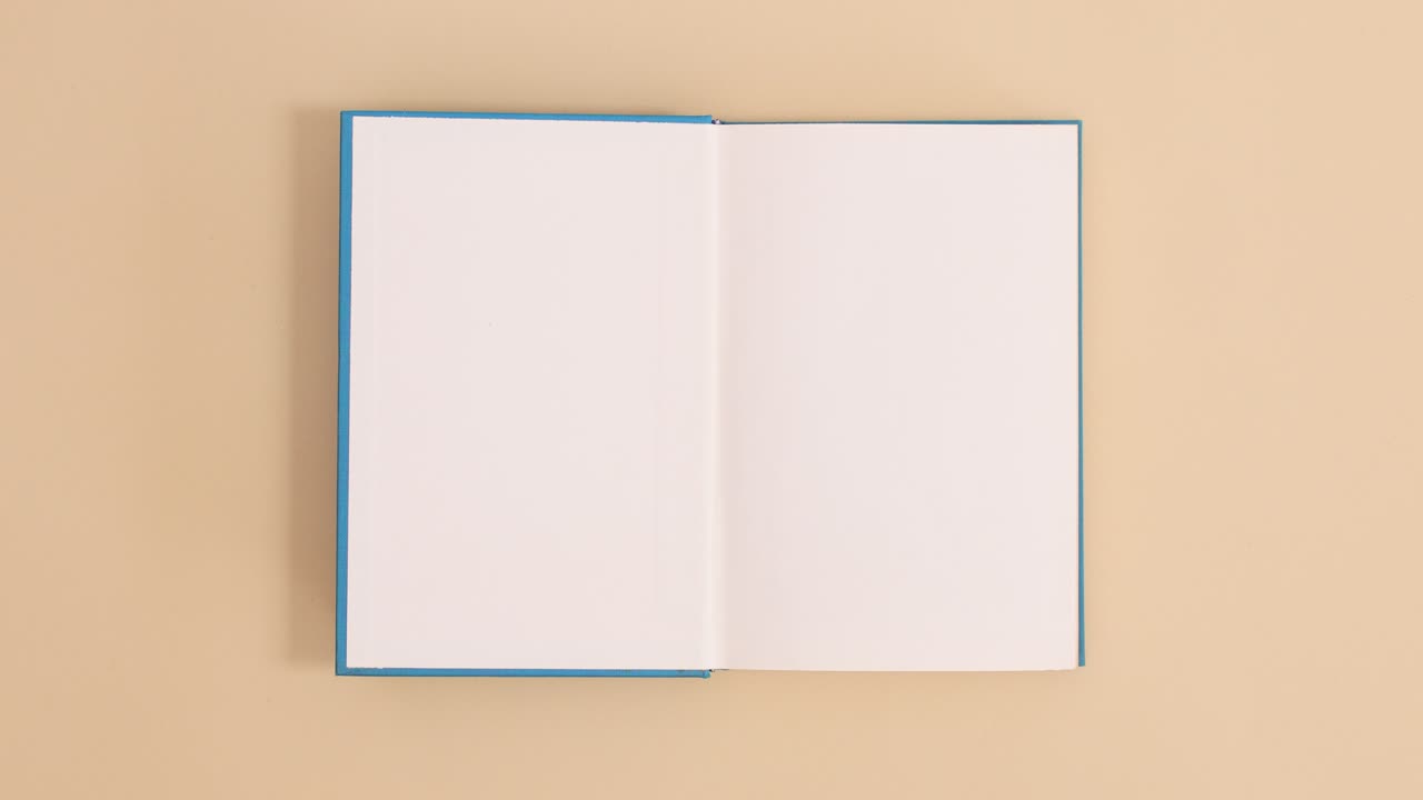 Blue hardcover vintage book appear and open with copy space on beige background. Stop motion flat lay