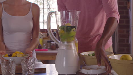 mixed race couple making smoothies using blender, close up, shot on r3d