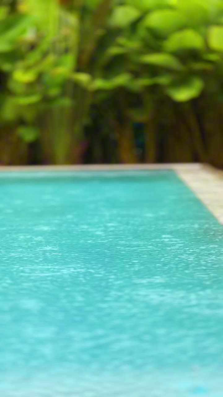 Destinazione tropicale durante la stagione dei monsoni piovosa, gocce di pioggia sulla superficie della piscina