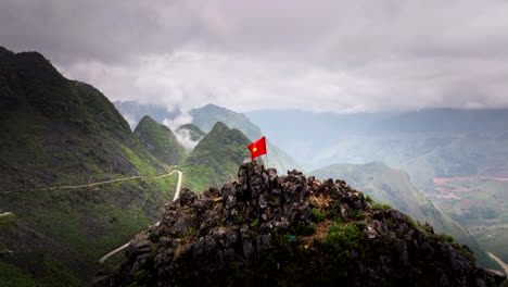 las olas de la bandera vietnamita en la brisa en lo alto de un afloramiento rocoso en la región montañosa del karst