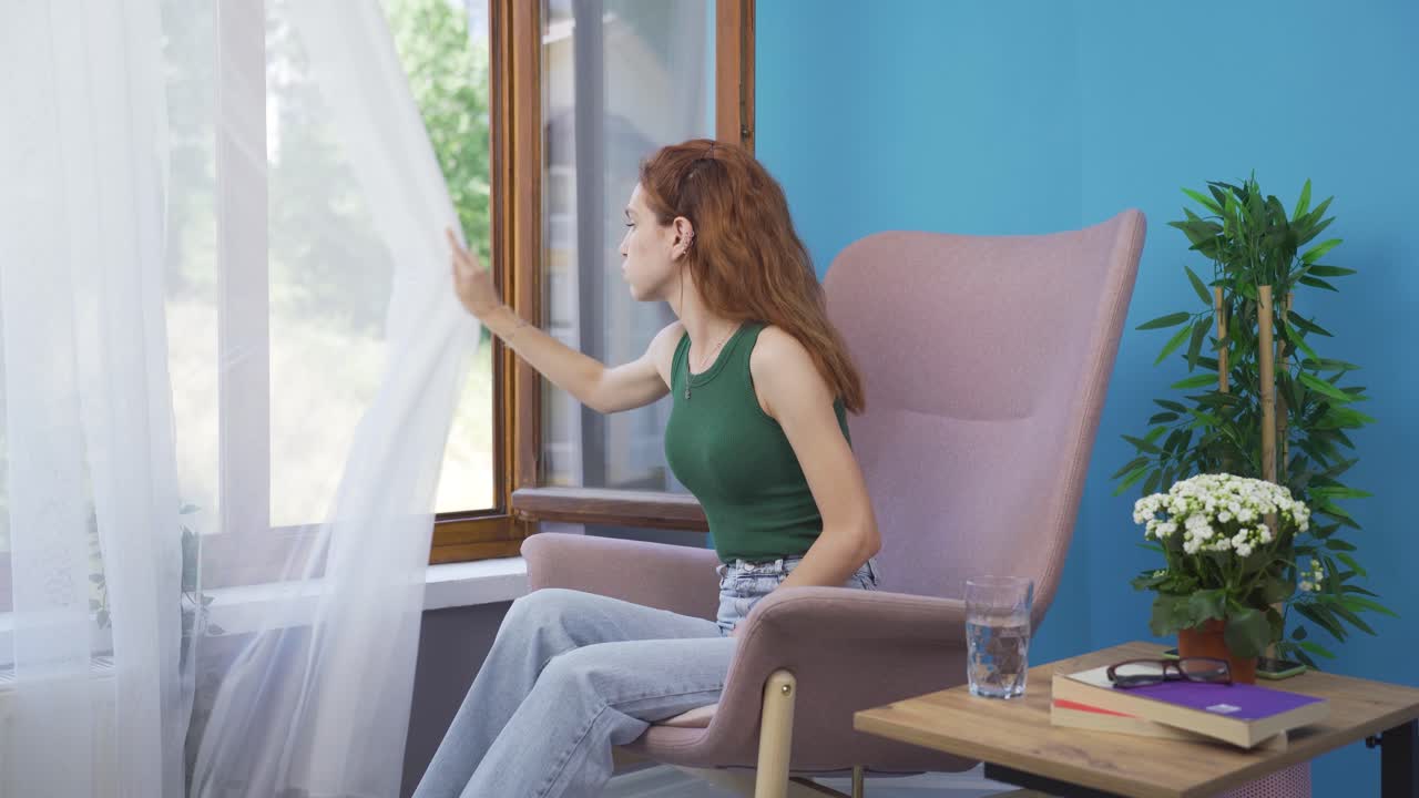 집의 커튼을 닫는 여자.