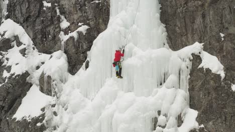 Ein-Einzelner-Bergsteiger-Klettert-Die-Gefrorene-Kaskade-Hinauf,-Spektakuläre-4K-Luftaufnahme