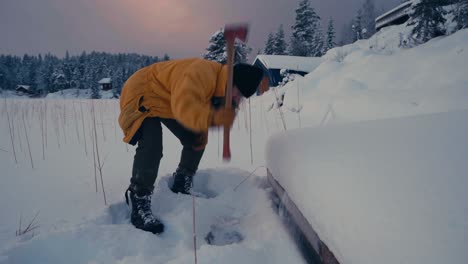 a guy with axe is breaking thick ice of a frozen lake