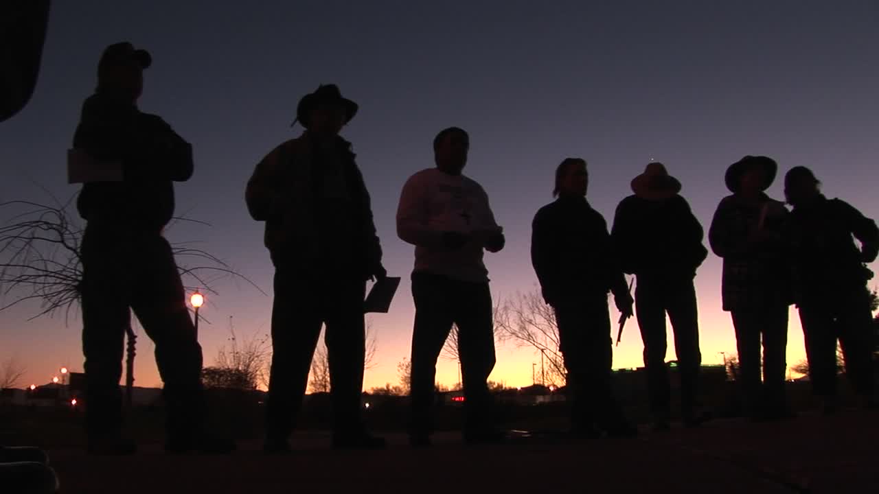 이른 아침 시간에 7~8명의 남자가 서류를 들고 서서 기다리고 있습니다.