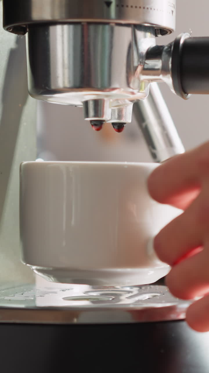 커피 머신으로 음료를 만드는 여인. 젊은 여성이 기계에서 커피 컵을 가져옵니다. 조심스러운 여성이 아침 식사를 준비 한 편안한 아침 장면