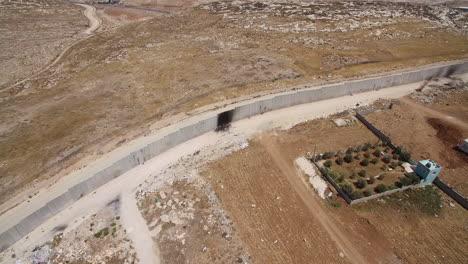 aerial view of a concrete security wall in a dry, arid landscape