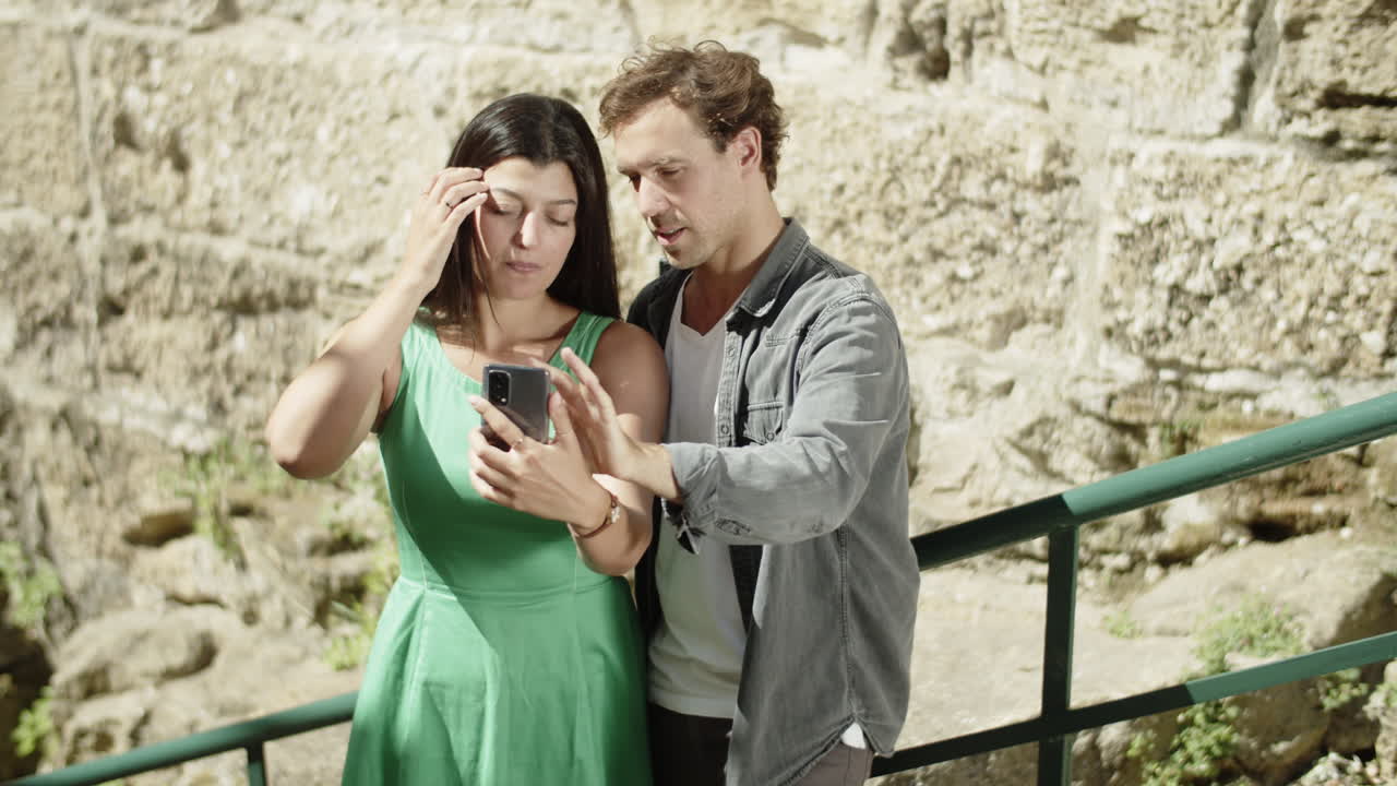 una pareja joven mirando fotos en su teléfono inteligente.