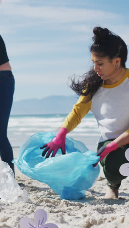 Animation-of-flowers-over-diverse-female-and-male-volunteers-picking-up-rubbish-on-beach