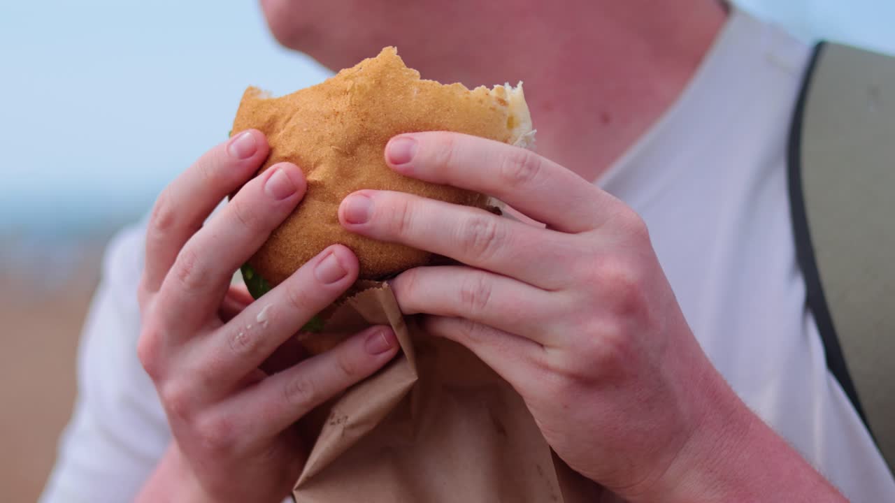 persona disfrutando de una hamburguesa en la playa de brighton