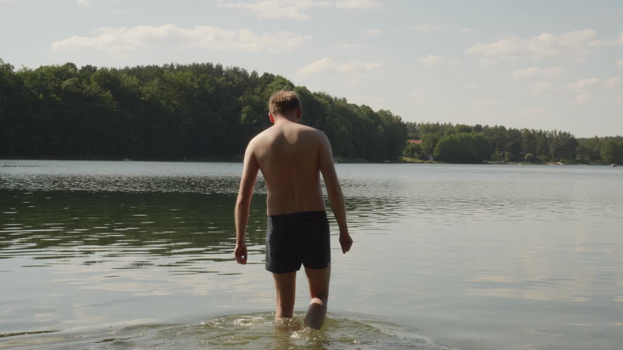 un hombre sin camisa nada en el lago de jezioro glebokie en polonia