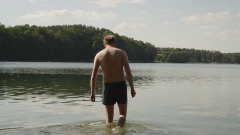 un hombre sin camisa nada en el lago de jezioro glebokie en polonia