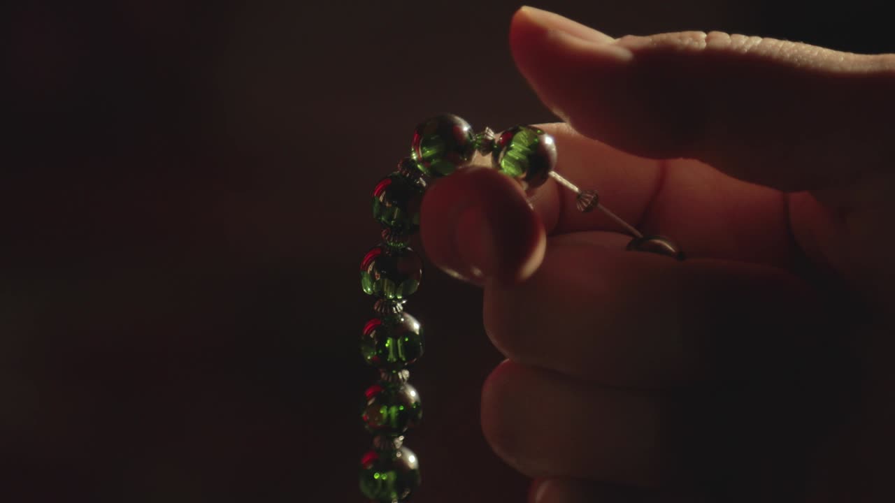 imágenes de cerca de una persona orando en sus cuentas de oración