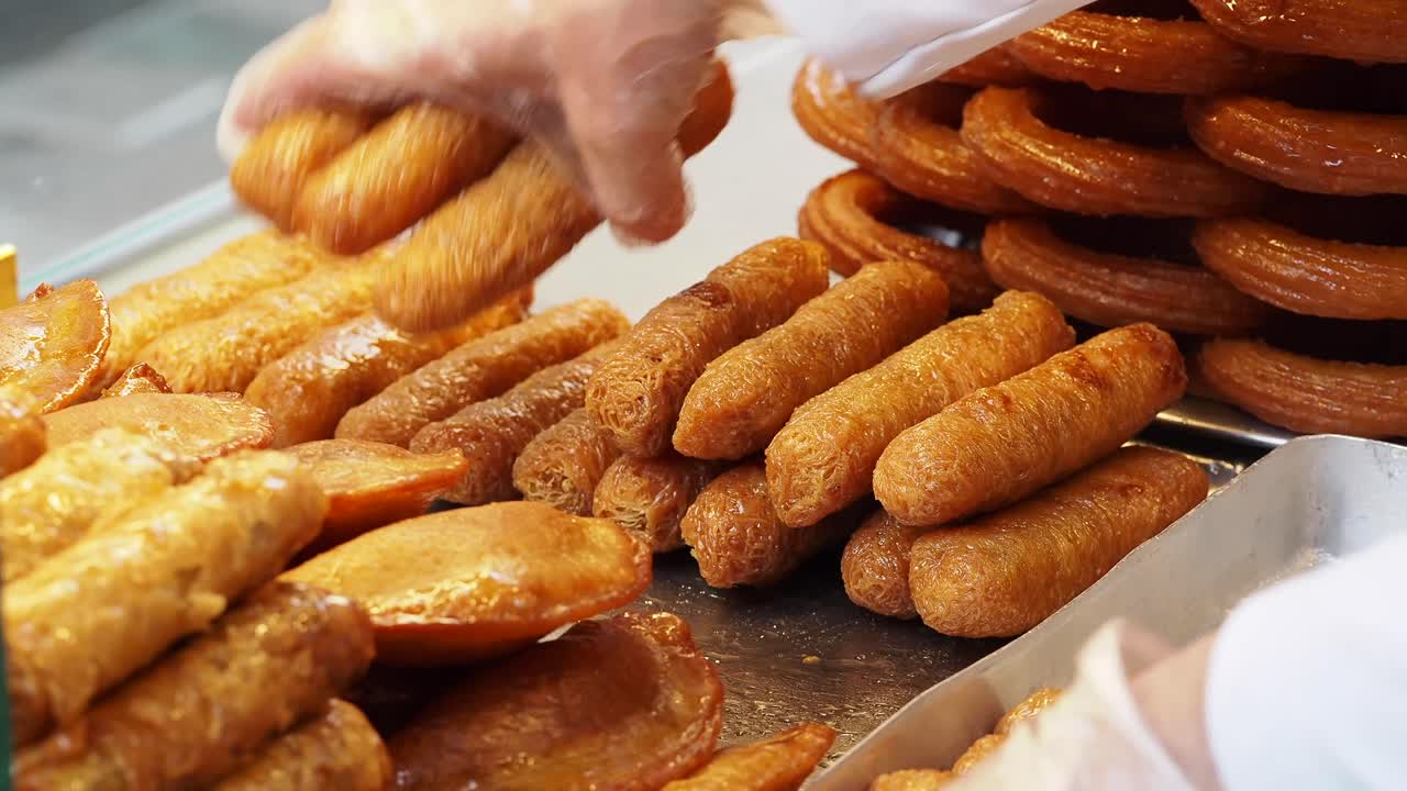 Mão Enluvada Organizando Doces Fritos Dourados com Calda em Exposição