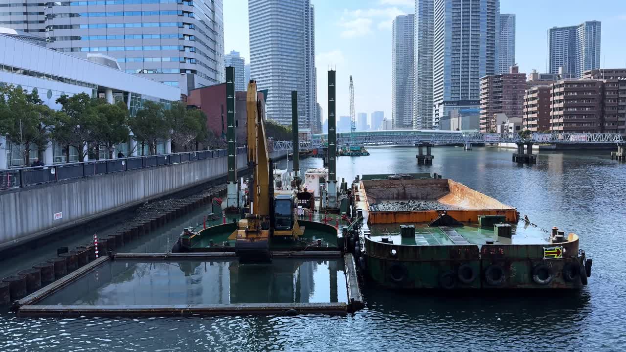 Barge operations with crane in the water near Harumi, Tokyo city skyline