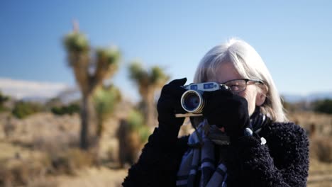 Eine-Erwachsene-Fotografin,-Die-Mit-Ihrer-Altmodischen-Filmkamera-Und-Ihrem-Objektiv-In-Einer-Wüstenlandschaft-Aus-Nächster-Nähe-Fotografiert