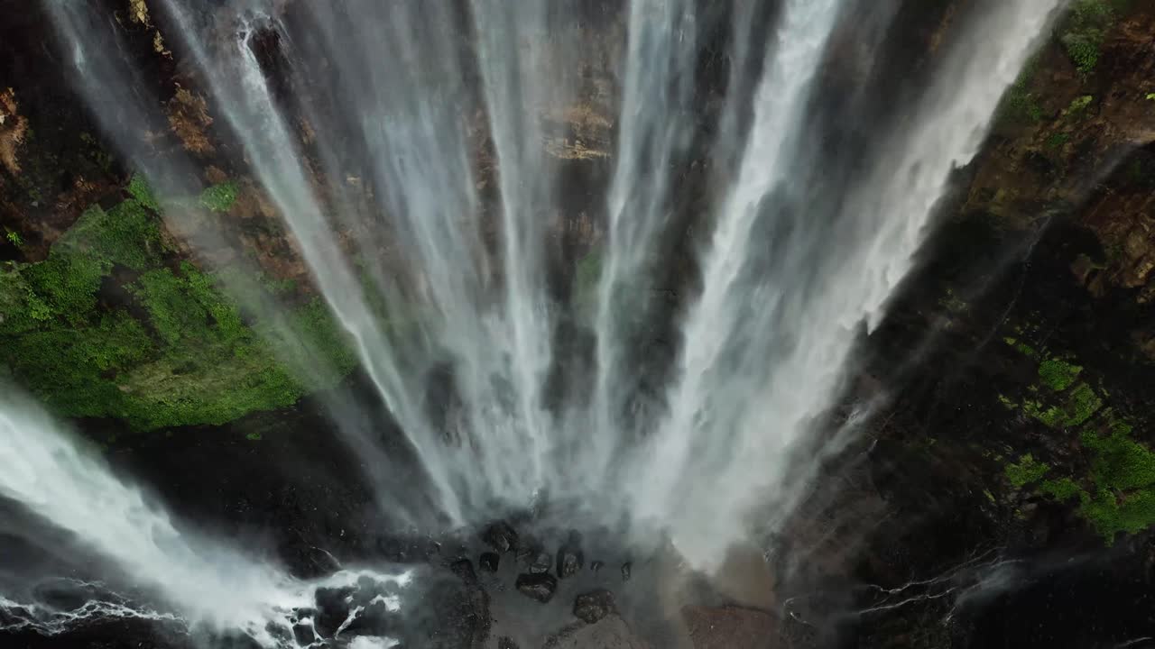 A stunning view of a waterfall cascading into a flowing river, surrounded by lush natural scenery. The rhythmic motion of water and ambient sounds evoke tranquility,