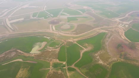 aerial view flying above misty foggy asian agricultural green patchwork farmland