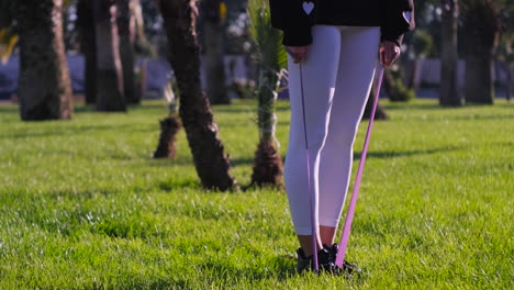 woman doing resistance band exercises in a park