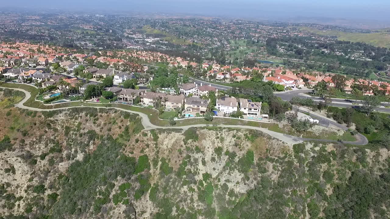 Aerial drone flyover panning across luxury homes in Laguna Niguel, Orange County, California that face Aliso Creek
