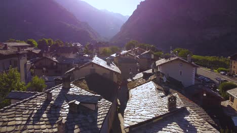 italian alps village next to mountains, closing aerial drone shot with backwards motion